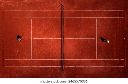 Top view of two people playing recreational tennis on a clay court during the day. - Powered by Shutterstock