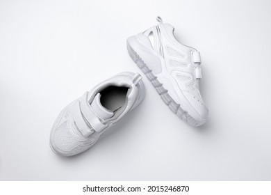 top view of two white children sneakers with velcro fasteners for easy footwear isolated on a white background.
