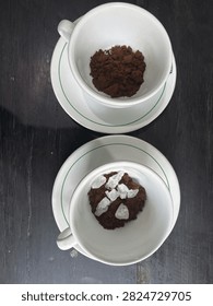 Top view of two white cups with ground black coffee powder and white rock sugar crystals, traditional coffee preparation

