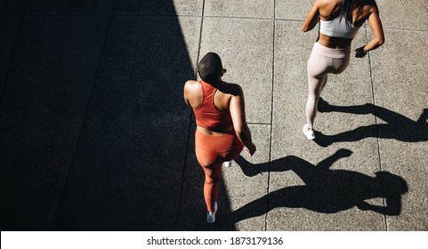 Top View Of A Two Women In Running Attire Jogging Together. Female  Friends Working Out Together In Morning.