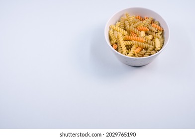 A Top View Of Uncooked Tri-color Rotini Pasta On A Bowl Isolated On White Background