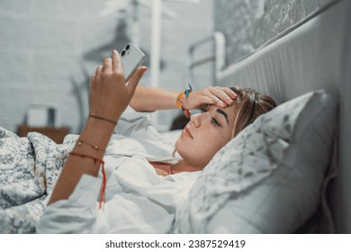 Top view unhappy woman feeling headache after sudden awakening by phone call, message signal or alarm in early morning, exhausted young female suffering from insomnia or migraine, lying in bed