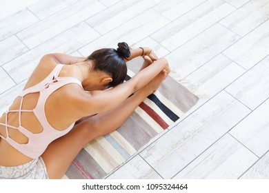 Top View - Unidentified Young Woman Doing An Exercise Of Yoga - Maha Mudra Sitting On Rug In The Gym. Copyspace