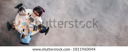 Top view of university students sitting at a table studying and working on laptop