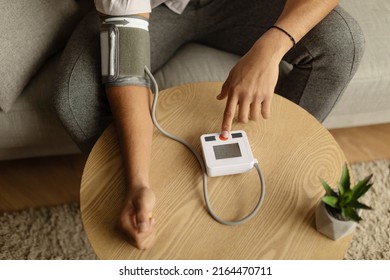 Top View Of Unrecognizable Black Male Patient Using Modern Tonometer At Home, Closeup. Young African American Man Measuring His Blood Pressure, Making Self Checkup Indoors