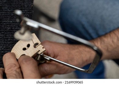 Top view of unrecognizable Latin American luthier using a hacksaw to finish making a violin bridge. Concept of stringed instruments