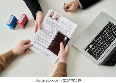 Top view of unrecognizable man applying for visa in immigration office and handing documents to worker