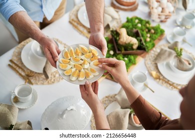 Top view of unrecognizable people sharing with egg during easter dinner - Shutterstock ID 2126656448