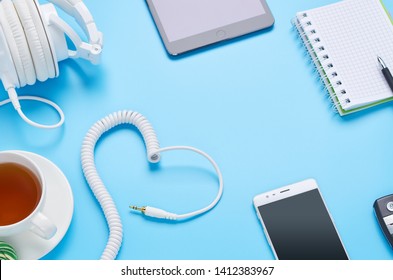 top view upon gadgets on blue background, composition of headphones, phone, tablet, glass with a drink and car keys - Shutterstock ID 1412383967
