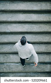 Top View Of Urban Athlete Running Upstairs. Sporty Man Working Out Outside And Climbing Stairs In Rainy Winter.