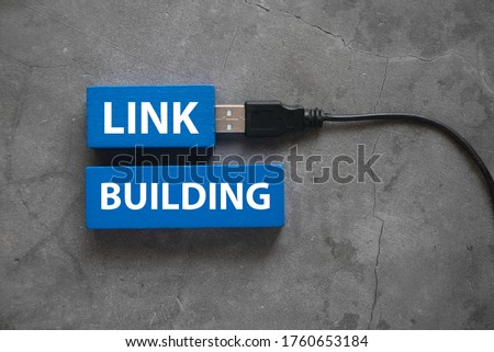 Top view of a usb cable and blue wooden cube written with Link Building on grey background.