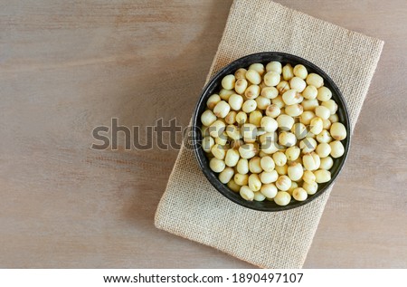 top view of vacuum fried lotus seeds in a ceramic bowl on wooden table. healthy food concept.