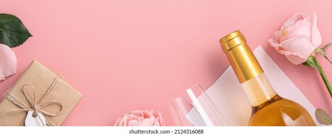 Top View Of Valentine's Day Gift With Wine And Pink Rose Bouquet On Pink Background Design Concept