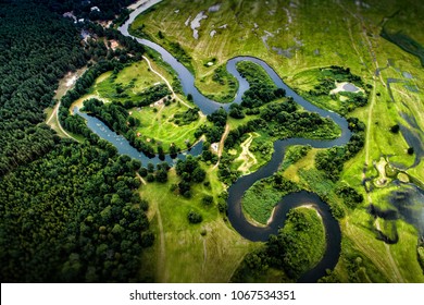 Top view of the valley of a meandering river among green fields and forests - Powered by Shutterstock