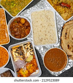Top View Of A Variety Of Indian Takeout Food In White Plastic Containers On A Fabric Background. 