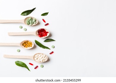 Top View Variety Of Vitamin And Mineral Pills In Wooden Spoon On Colored Background. Top View Of Assorted Pharmaceutical Medicine Pills. Dietary Supplement Healthcare Product.