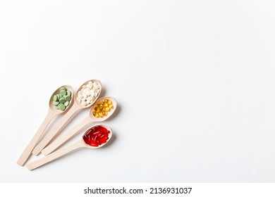 Top view Variety of vitamin and mineral pills in wooden spoon on Colored background. Top view of assorted pharmaceutical medicine pills. Dietary supplement healthcare product.