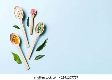 Top view Variety of vitamin and mineral pills in wooden spoon on Colored background. Top view of assorted pharmaceutical medicine pills. Dietary supplement healthcare product.