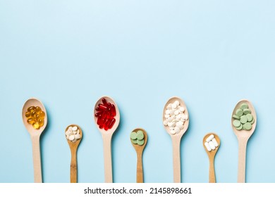 Top View Variety Of Vitamin And Mineral Pills In Wooden Spoon On Colored Background. Top View Of Assorted Pharmaceutical Medicine Pills. Dietary Supplement Healthcare Product.