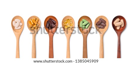 Top view Variety of vitamin and mineral pills in wooden spoon isolated on white background, Dietary supplement healthcare product.