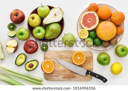 Top view of various colorful fresh summer fruits, Sliced fruits and a knife on cutting board isolated over white background, Horizontal shot