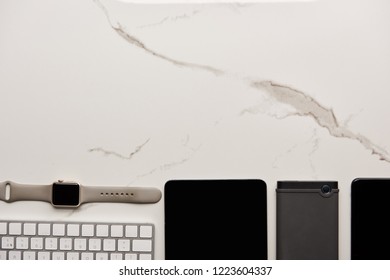 top view of various wireless gadgets on white marble surface