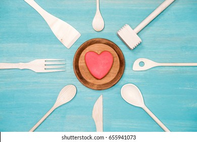 Top View Of Various Wooden Cooking Utensils With Heart Symbol On Plate