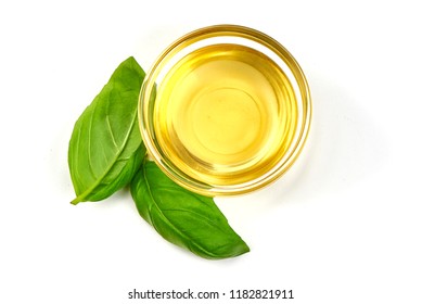 Top View Of Vegetable Or Olive Oil In A Bowl With Basil Leaves, Isolated On White Background.