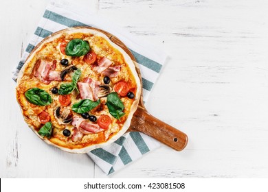 Top view VERY HOT Italian Pizza on white wooden table with mushrooms, basil, tomato, olives and cheese. Look as Prosciutto, Capricciosa, HOMEMADE PIZZA with decoration. Photo with space for text.  - Powered by Shutterstock