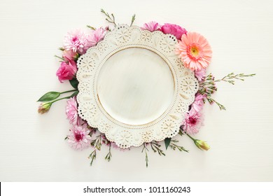 Top view of vintage white empty plate over spring flowers. Flat lay