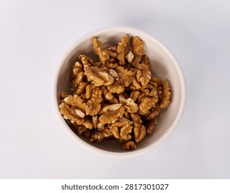 Top view of walnut kernels in a ceramic bowl isolated on white background
