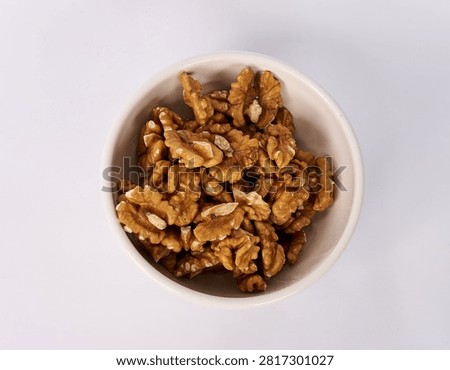 Top view of walnut kernels in a ceramic bowl isolated on white background

