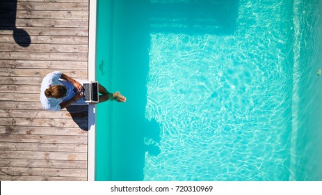 top view of well dressed male sitting at the pool with laprop and working - Powered by Shutterstock