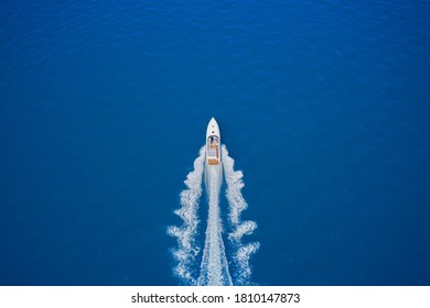 Top view of a white boat sailing in the blue sea. luxury motor boat. Aerial view of a boat in motion on blue water. Drone view of a boat sailing at high speed.