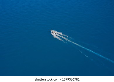 Top View Of A White Boat Sailing To The Blue Sea. High-speed Boat Of White Color Fast Motion On Blue Water In The Rays Of The Sun Top View. Travel - Image.  Aerial View Luxury Motor Boat.