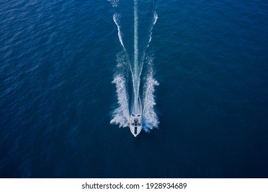 Top view of a white boat sailing in the blue sea. Top view of the boat. Aerial view luxury motor boat.  A boat with a motor on blue water.