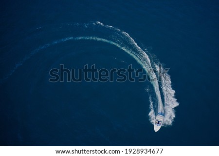 Top view of a white boat sailing in the blue sea. A boat with a motor on blue water in a turn. Top view of the boat. Aerial view luxury motor boat.
