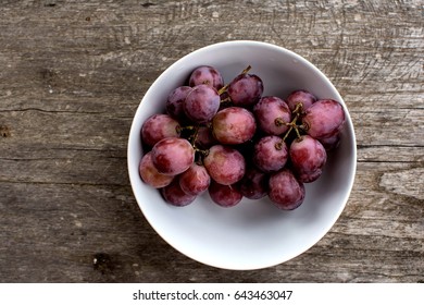 Top view a white bowl of grapes on old wooden  table