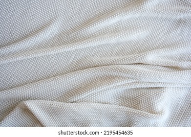 Top View Of White Crumpled Knitted Blanket. Texture Background