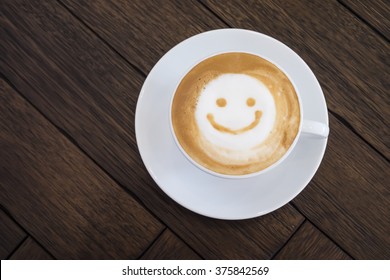 Top View White Cup Of Latte Art Happy Smile Face On Brown Wooden Table Background With Copyspace.