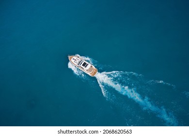 Top view of a white high-speed boat. Yacht movement on blue water top view. Luxury yacht on the water aerial view. White yacht fast movement on the water top view. Travel - image.