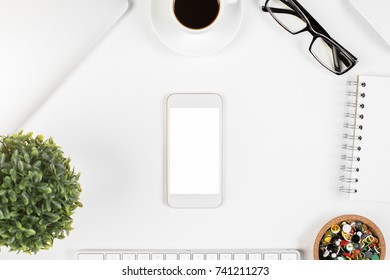 Top View Of White Office Desk With Electronic Devices, Supplies, Coffee Cup And Other Items. Mock Up