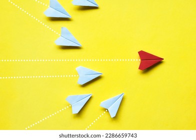 Top view of white paper airplanes origami chasing red airplane on yellow background with customizable space for text or ideas. Leadership skills concept and copy space