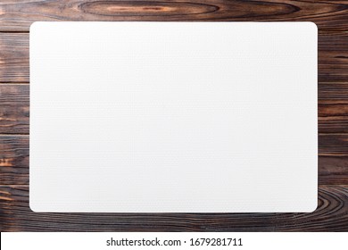 Top view of white place mat for a dish. Wooden background with empty space for your design.