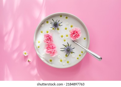 Top view of the white plate with spoon, milk and pink, white and blue flowers, on pink background with shades and sunlight - Powered by Shutterstock