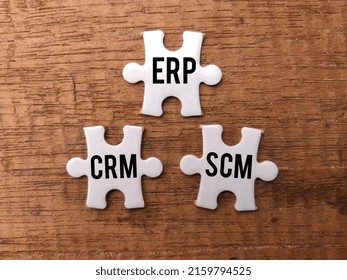 Top View White Puzzle With The Word ERP CRM SCM On A Wooden Background.