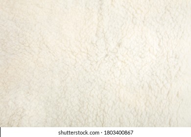 Top View Of White Soft Sheepskin Textile Plaid. Warm Cozy Background.