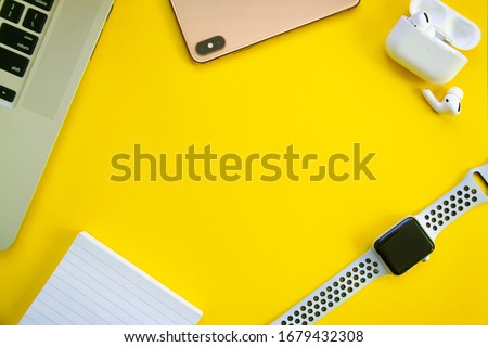 Top view of white table computer, phone, headphones, watch and notebook