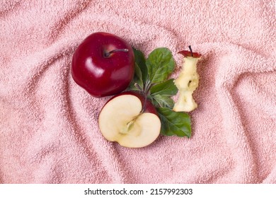 Top View Of Whole, Half Apple And Apple Core With Green Leaves On Fur Pink Towel Flat Lay.