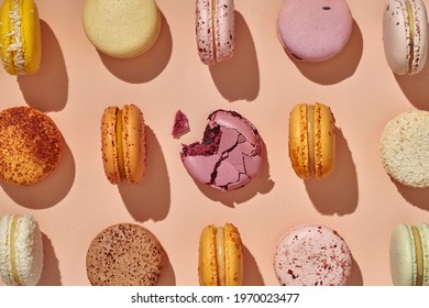 Top view of whole macarons and one bitten in center on pink background